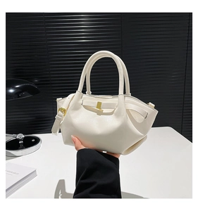 Detail of cream oil wax leather bucket bag featuring pleated sides and gold buckle hardware