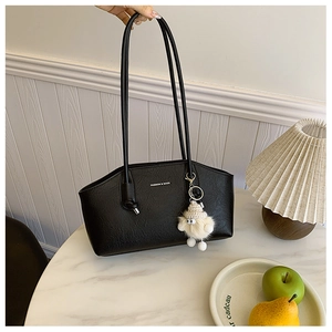 Detail view of black lychee-textured leather tote bag with stylish plush sheep pendant