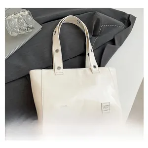 Détail du sac cabas crème avec des œillets métalliques argentés et une large sangle