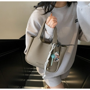 Close-up of taupe lychee-grain leather tote bag with top handles and fashion charms