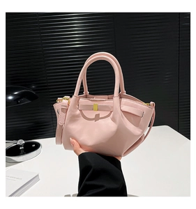 Macro detail of pink wax leather bucket bag featuring unique pleated bow design and gold hardware