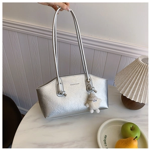 Detail of silver metallic pleated shoulder bag with fashion text and fluffy doll charm