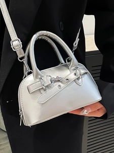 Chic silver metallic shell bag with dual handles and crossbody strap on a black suit