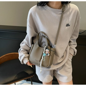 Detail of grey lychee texture bucket bag with gold lettering and cute bear charm