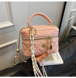 Gros plan sur le mini sac boîte rose matelassé avec chaîne dorée et détail floral