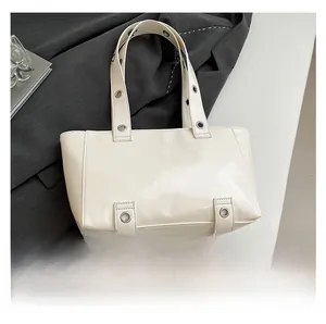 Détail du sac cabas crème avec œillets métalliques argentés et texture en cuir ciré lisse