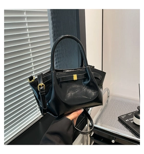 Detail of black glossy leather bucket bag with gold hardware and stylish pleated design