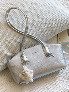 Silver metallic underarm bag with pleated texture and white plush charm on white background