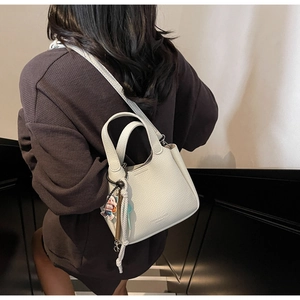 Detailed close-up of white lychee pattern leather handbag with fashion doll pendant accessory