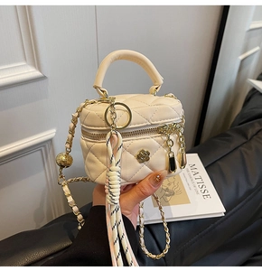 Vue macro détaillée du sac boîte en cuir crème matelassé avec accents floraux dorés et chaîne