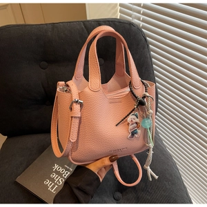 Pink lychee grain leather bucket bag with cute dog pendant and adjustable strap detail
