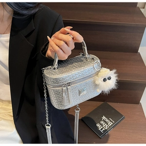 Detail of silver woven texture box bag with metallic chain and white pompom charm