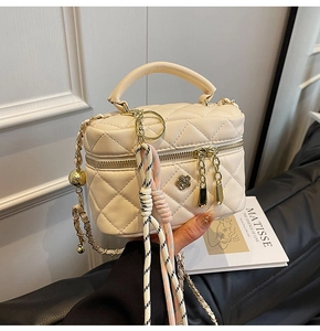 Vue détaillée du sac boîte matelassé crème avec boucle fleur dorée et bandoulière