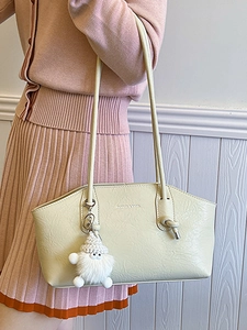 Beige textured leather underarm bag with metal rings and plush charm pendant