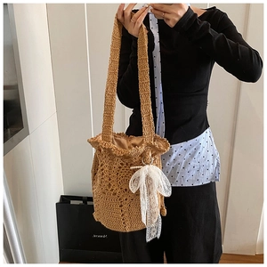 Detail der handgewebten Häkel-Beuteltasche in Khaki mit Lochmuster und Spitzenschleife