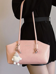 Pink minimalist shoulder bag in wrinkled leather texture with plush pendant accessory