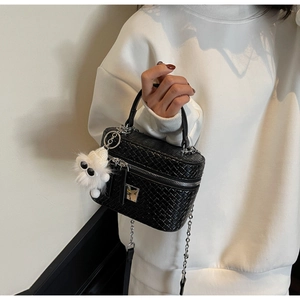 Detail of black woven vanity bag with silver chain strap and white plush monster charm