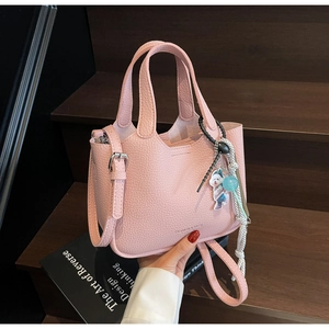 Close-up of pink litchi grain bucket bag with cute dog charm and silver metal hardware
