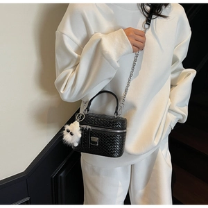 Detail of woven texture handbag with silver chain and white plush doll pendant
