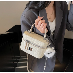 Detail of cream woven pattern box bag with silver hardware and plush pendant