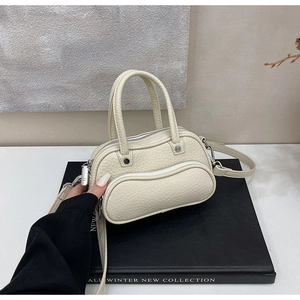 Detailed macro view of the cream lychee grain leather bowl bag with silver zippers