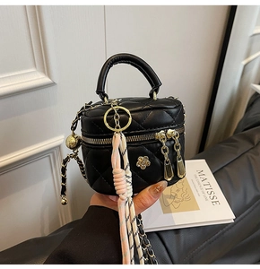 Détail du mini sac boîte noir matelassé avec fermetures dorées et pendentif fleurie