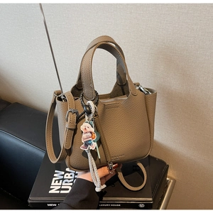 Detailed macro view of litchi grain leather texture on brown tote with cute bear charm