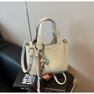 Detail of lychee pattern leather bucket bag with cute bear charm and fashion text logo