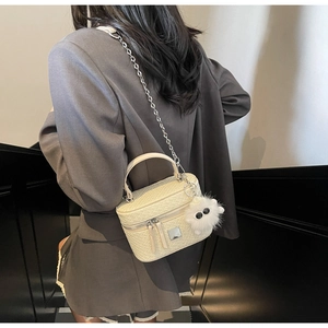 Detail of white woven box bag with silver chain and cute plush monster charm