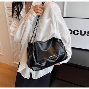 Détail d'un sac bandoulière en cuir noir avec chaîne, boucle argentée et rabat moderne