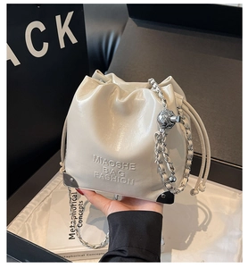 Detail of cream drawstring bucket bag with MIAOSHE embossed logo and silver chain strap