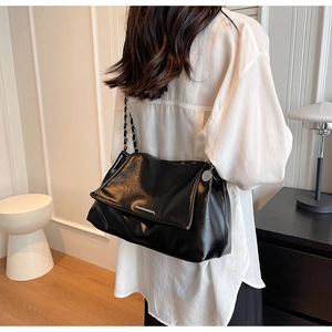 Gros plan du sac cabas en cuir noir avec bandoulière chaîne porté par un mannequin femme