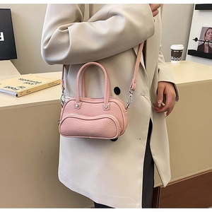 Detailed view of pink lychee texture leather bowling bag held by a model in a suit