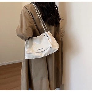 Détail d'un sac cabas en cuir plissé blanc avec bandoulière en chaîne argentée élégante