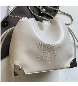 Close-up of cream leather bucket bag showing embossed text and silver corner protectors