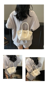 Detailansicht der cremefarbenen Eimer-Tasche aus Ölwachsleder mit Zierschnalle und Riemen