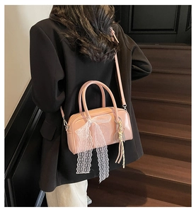 Detailed view of a pink pillow bag featuring white lace bow and woven tassel pendant