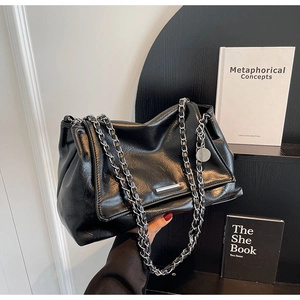 Détail du sac cabas noir en cuir huilé avec chaîne argentée et ornements métalliques
