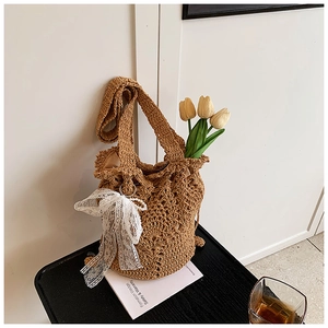Detail der handgewebten Strohtasche mit Lochmuster und weißer Spitzenschleife