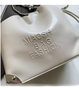 Detailed macro view of the cream leather bucket bag with embossed MIAOSHE BAG FASHION logo
