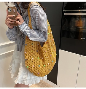 Detail of yellow knit shoulder bag with colorful pearls for a bohemian vacation style