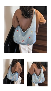 Dettaglio della borsa tote in tela azzurra con ricami a cartoni animati e scritte Good Vibes