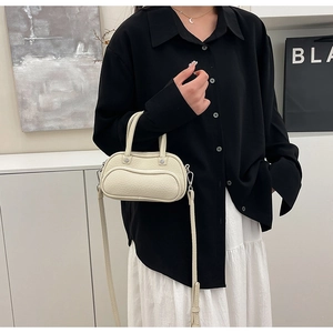 Chic beige lychee leather mini bowling bag styled with a minimalist outfit on a model