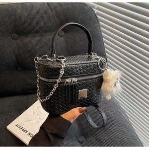 Detail of black woven box bag with metal chain strap and white plush charm on the side
