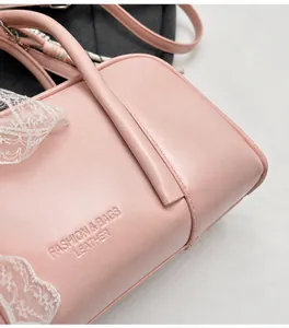 Detailed macro view of pink leather pillow bag featuring white lace trim and logo