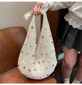 Detail of hand-crocheted knit tote bag featuring colorful faux pearls and openwork texture