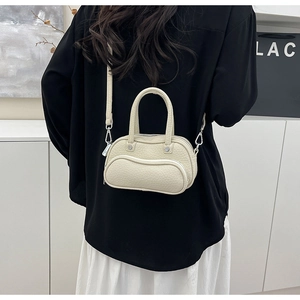 Detail view of cream white litchi pattern mini bowling bag with wavy zipper design