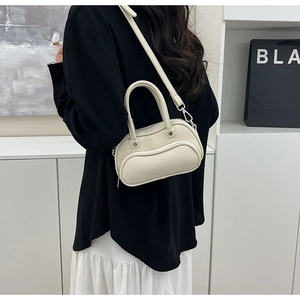 Close-up of cream lychee texture leather mini bowling bag with silver hardware detail