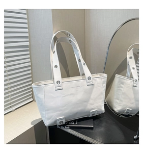 Vue détaillée du cuir ciré blanc et des œillets argentés sur le sac fourre-tout