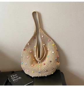 Detail of beige crochet tote bag with colorful beads and wide strap on leather base